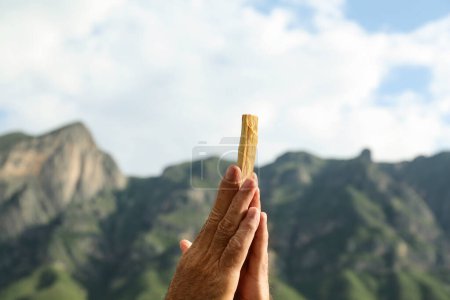 Photo for Man holding palo santo stick in high mountains, closeup - Royalty Free Image