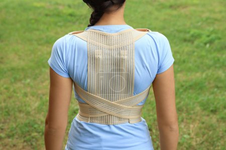 Photo for Closeup of woman with orthopedic corset on green grass outdoors, back view - Royalty Free Image
