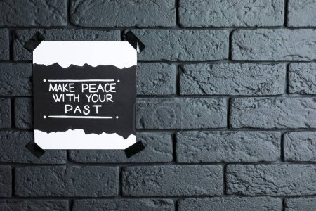 Téléchargez les photos : Carte avec phrase affirmant la vie Faites la paix avec votre passé sur un mur de briques sombres. Espace pour le texte - en image libre de droit