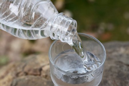 Foto de Verter agua de la botella en el vidrio al aire libre, de cerca - Imagen libre de derechos