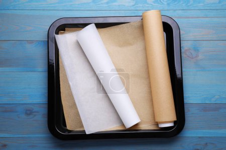Téléchargez les photos : Rouleaux de papier parchemin dans une plaque de cuisson sur une table en bois bleu clair, vue sur le dessus - en image libre de droit