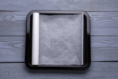 Téléchargez les photos : Rouleau de papier parchemin avec plaque à pâtisserie sur table en bois gris, vue de dessus - en image libre de droit