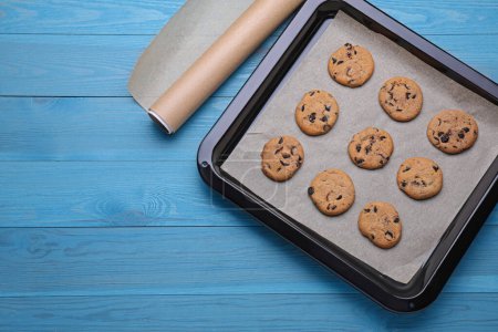 Téléchargez les photos : Papier sulfurisé et plaque à pâtisserie avec de savoureux biscuits sur une table en bois bleu clair, à plat. Espace pour le texte - en image libre de droit