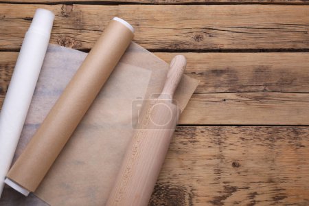 Téléchargez les photos : Rouleaux de papier sulfurisé et rouleau à pâtisserie sur table en bois, vue de dessus. Espace pour le texte - en image libre de droit