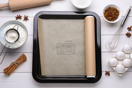 Téléchargez les photos : Poêle à pâtisserie avec papier parchemin, différents ingrédients et outils de cuisine sur table en bois blanc, pose plate - en image libre de droit