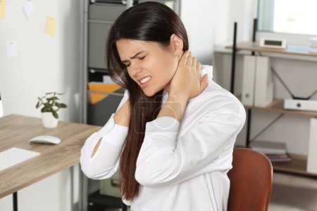 Jeune femme souffrant de douleurs au cou au bureau

