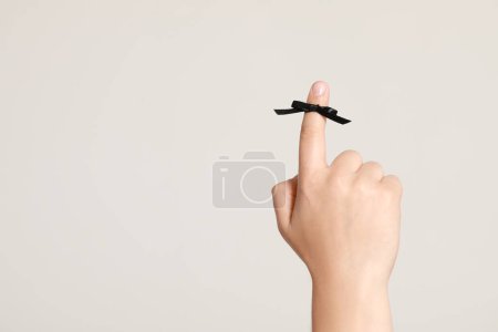 Photo for Man showing index finger with black tied bow as reminder on white background, closeup. Space for text - Royalty Free Image