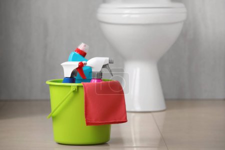 Téléchargez les photos : Seau avec des fournitures de nettoyage de toilettes sur le sol à l'intérieur, espace pour le texte - en image libre de droit