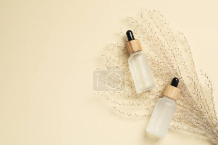 Photo for Bottles of face serum and dried flowers on beige background, flat lay. Space for text - Royalty Free Image