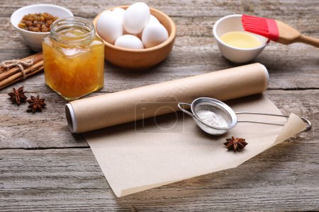 Téléchargez les photos : Rouleau de papier sulfurisé, différents ingrédients et outils de cuisine sur table en bois - en image libre de droit