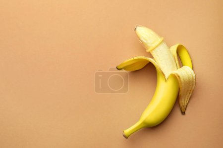Téléchargez les photos : Banane avec préservatif sur fond orange pâle, vue de dessus et espace pour le texte. Concept de sexe sûr - en image libre de droit