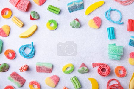 Foto de Marco de muchos sabrosos caramelos de jalea de colores en la mesa blanca, la puesta plana. Espacio para texto - Imagen libre de derechos