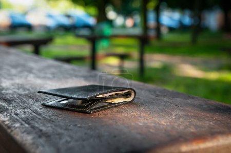 Téléchargez les photos : Portefeuille noir sur banc à l'extérieur. Perdu et trouvé - en image libre de droit