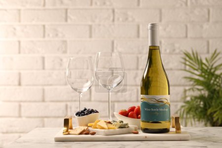 Foto de Botella de vino, copas y deliciosos aperitivos sobre mesa de mármol blanco - Imagen libre de derechos