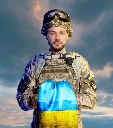 Foto de Soldado en uniforme militar con bandera ucraniana contra el cielo nublado - Imagen libre de derechos
