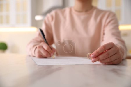 Photo for Woman with wedding ring signing divorce papers at table indoors, closeup. Space for text - Royalty Free Image