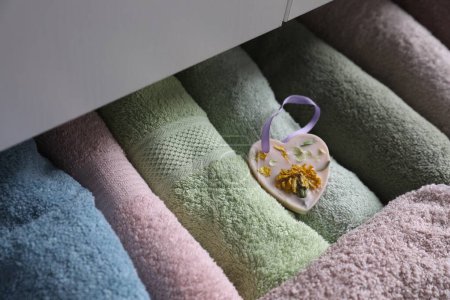 Photo for Beautiful heart shaped scented wax sachet in dresser drawer with colorful towels, closeup - Royalty Free Image