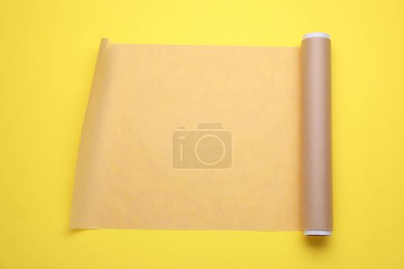 Téléchargez les photos : Rouleau de papier cuisson sur fond jaune, vue de dessus - en image libre de droit