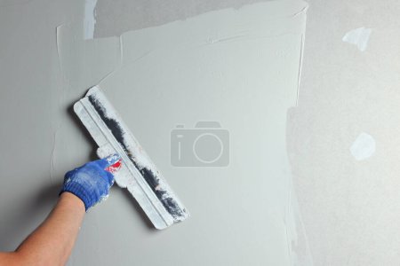 Photo for Professional worker plastering wall with putty knife, closeup - Royalty Free Image
