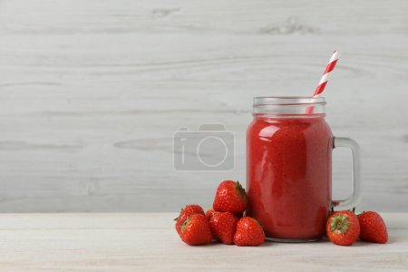 Einmachglas mit leckerem Erdbeer-Smoothie und frischen Beeren auf weißem Holztisch. Raum für Text