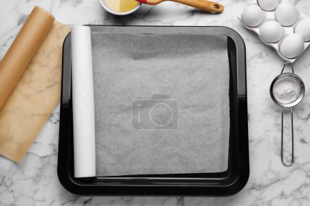 Téléchargez les photos : Poêle à pâtisserie avec papier sulfurisé, différents ingrédients et outils de cuisine sur table en marbre blanc, pose plate. Espace pour le texte - en image libre de droit