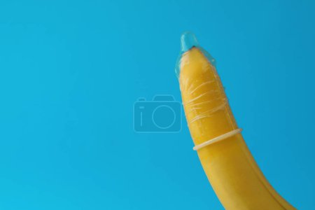 Téléchargez les photos : Banane avec préservatif sur fond bleu clair, gros plan et espace pour le texte. Concept de sexe sûr - en image libre de droit