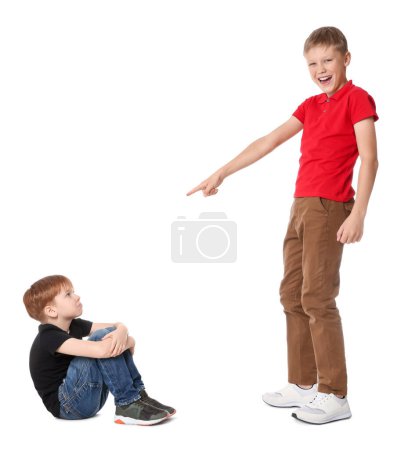 Boy laughing and pointing at upset kid on white background. Children's bullying