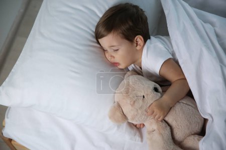 Téléchargez les photos : Mignon petit bébé dormant avec jouet à la maison. Au lit. - en image libre de droit
