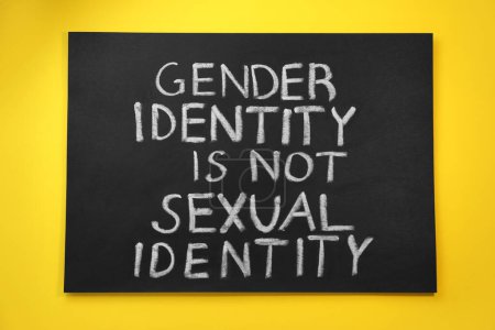 Téléchargez les photos : Tableau noir avec texte Identité de genre n'est pas l'identité sexuelle sur fond jaune, vue du dessus - en image libre de droit