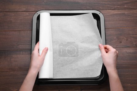 Téléchargez les photos : Femme mettant du papier parchemin dans un moule à pâtisserie sur une table en bois, vue sur le dessus. Espace pour le texte - en image libre de droit