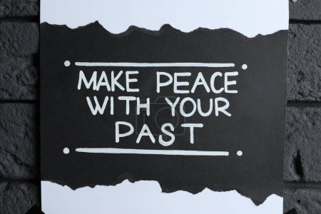 Téléchargez les photos : Carte avec phrase réaffirmant la vie Faire la paix avec votre passé sur un mur de briques sombres, gros plan - en image libre de droit