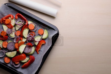 Téléchargez les photos : Plaque de cuisson avec légumes crus et papier parchemin sur table en bois, plat. Espace pour le texte - en image libre de droit
