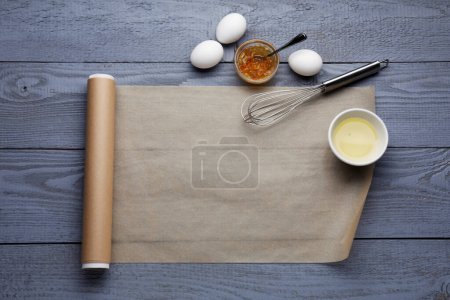Téléchargez les photos : Cuire du papier sulfurisé et des ingrédients sur une table en bois gris, poser à plat. Espace pour le texte - en image libre de droit