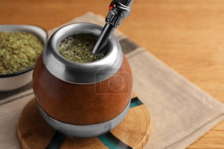 Calabash avec thé mat et bombilla sur table en bois, gros plan. Espace pour le texte