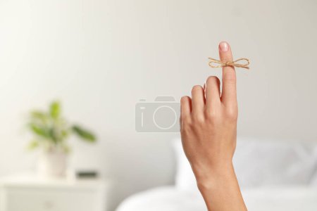 Photo for Woman showing index finger with tied bow as reminder indoors, closeup. Space for text - Royalty Free Image