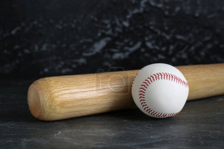 Bate de béisbol y pelota sobre fondo negro. Equipamiento deportivo