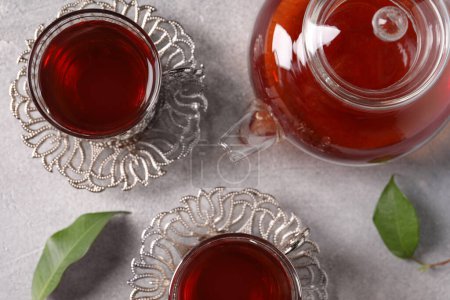 Téléchargez les photos : Verres de thé traditionnel turc dans des porte-cru et pot sur table gris clair, plat - en image libre de droit