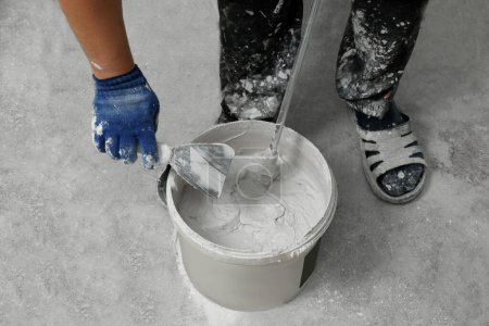 Téléchargez les photos : Travailleur professionnel mélangeant du plâtre dans un seau à l'intérieur, gros plan - en image libre de droit