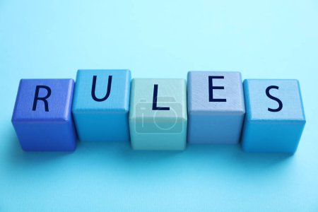 Word Reglas hechas de cubos de madera con letras sobre fondo azul claro, vista superior