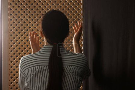Téléchargez les photos : Femme priant Dieu pendant la confession dans la cabine, vue de dos - en image libre de droit
