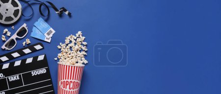 Foto de Composición plana con claqueta, entradas para cine y palomitas de maíz sobre fondo azul, espacio para texto. Diseño de banner - Imagen libre de derechos