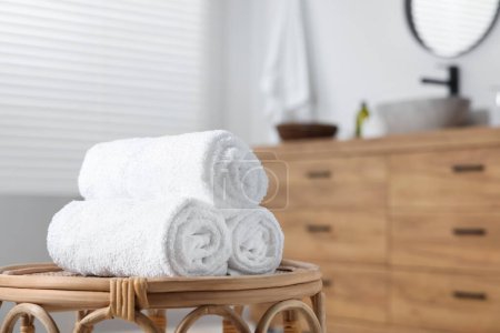 Rolled bath towels on wicker table in bathroom. Space for text