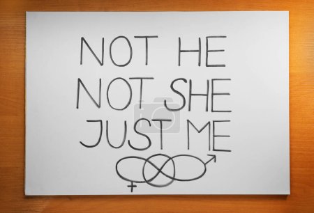 Card with text Not He Not She Just Me and gender symbols on wooden background, top view