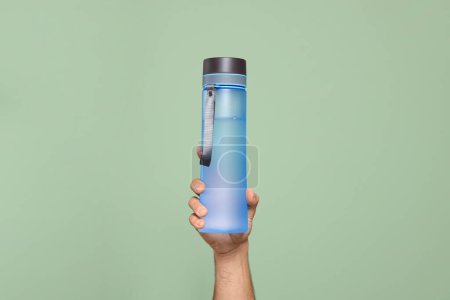 Téléchargez les photos : Homme tenant une bouteille d'eau en plastique transparent sur fond vert clair, gros plan - en image libre de droit
