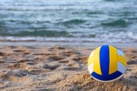 Téléchargez les photos : Ballon de volley coloré sur sable près de la mer. Espace pour le texte - en image libre de droit