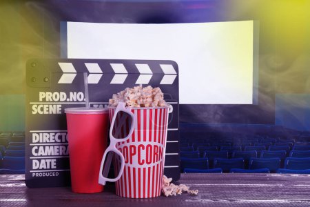 Photo for Delicious popcorn, drink, 3D glasses and clapperboard on wooden table in cinema, space for text - Royalty Free Image