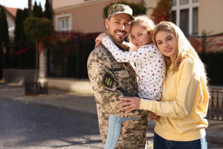 Soldado en uniforme militar ucraniano se reunió con su familia en la calle de la ciudad, espacio para el texto