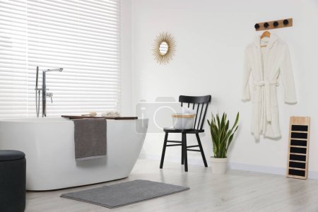 Foto de Elegante baño interior con bañera de cerámica, toallas de rizo y planta de interior - Imagen libre de derechos
