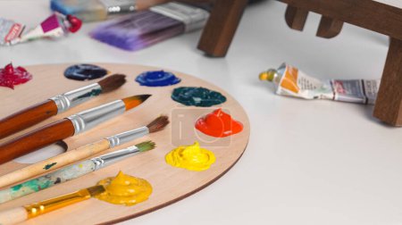 Foto de Paleta de artistas con muestras de coloridas pinturas y pinceles sobre mesa blanca. Espacio para texto - Imagen libre de derechos