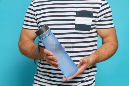 Téléchargez les photos : Homme tenant une bouteille d'eau en plastique transparent sur fond bleu clair, gros plan - en image libre de droit